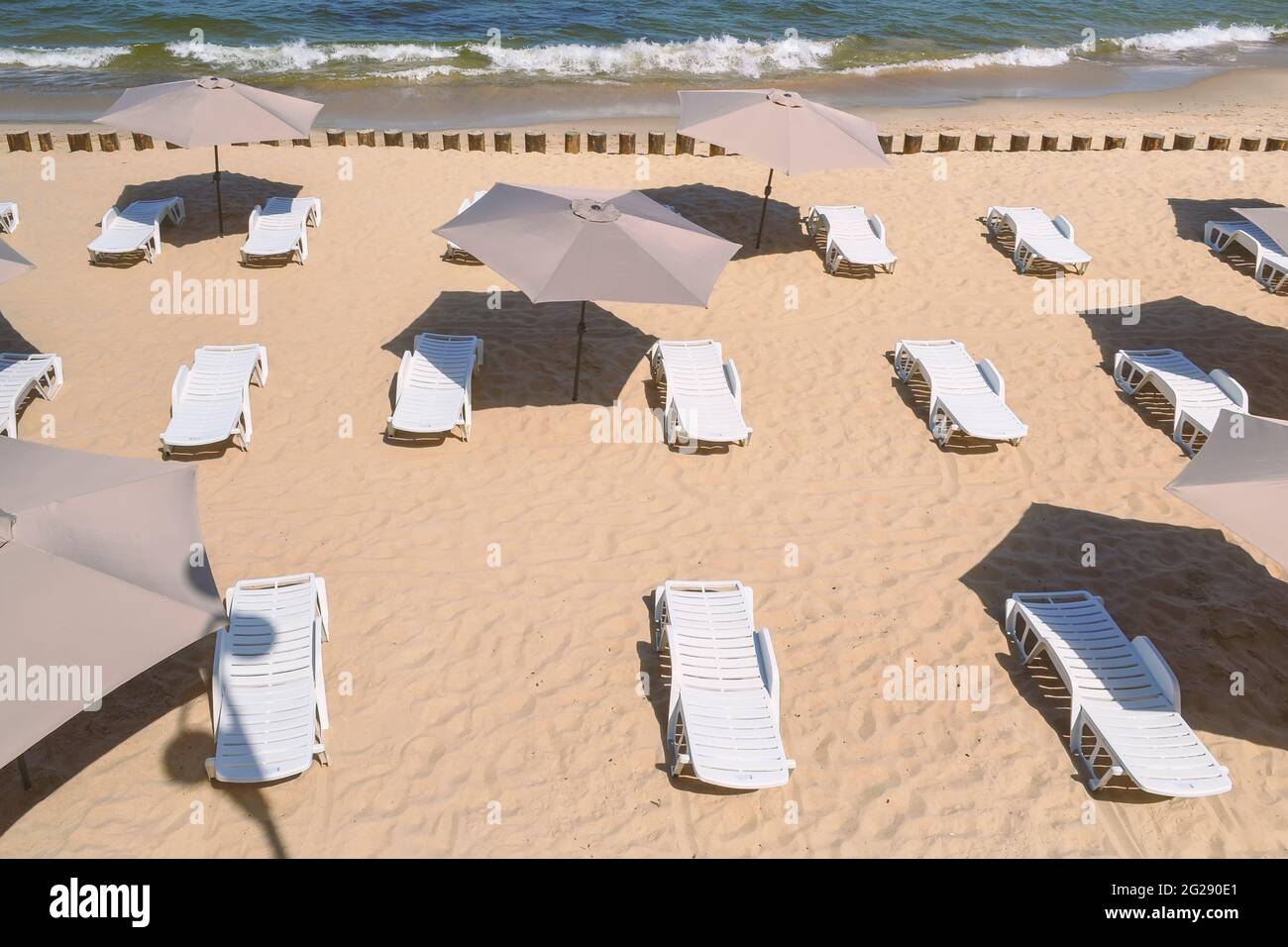 Sedie a sdraio e ombrelloni vuoti su una spiaggia di sabbia. Foto Stock