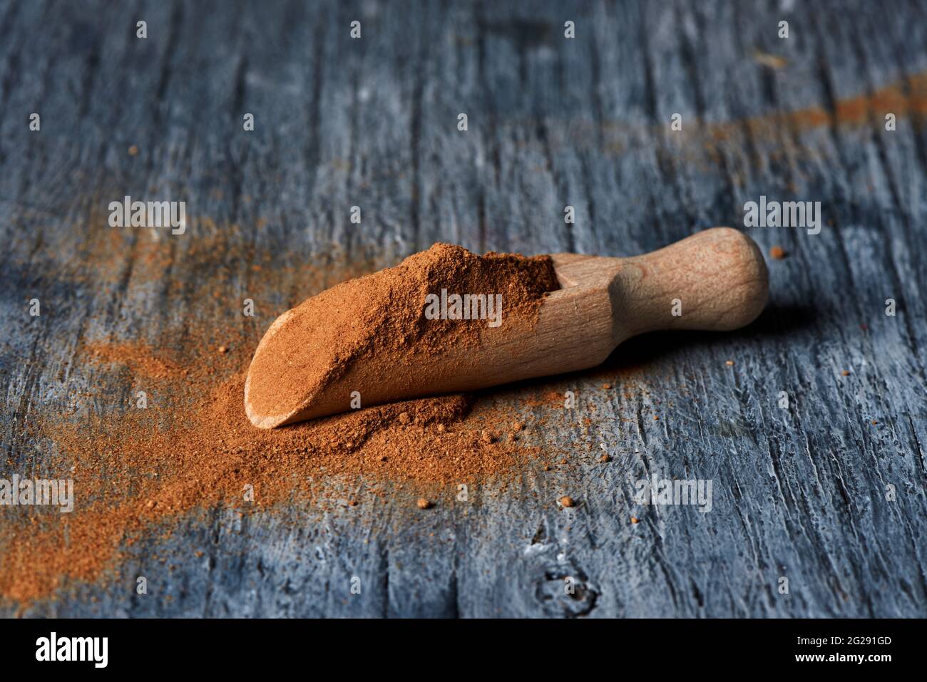 primo piano di un misurino in legno e pieno di polvere di camu-camu su un tavolo in legno rustico grigio Foto Stock