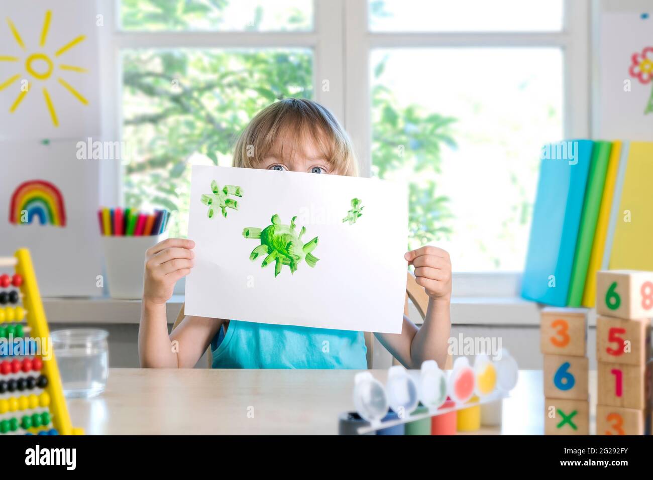 Divertente bello felice bambino ragazzo disegna ridendo con vernice. Spettacoli per bambini che annegano il coronavirus. Messa a fuoco selettiva. Foto Stock