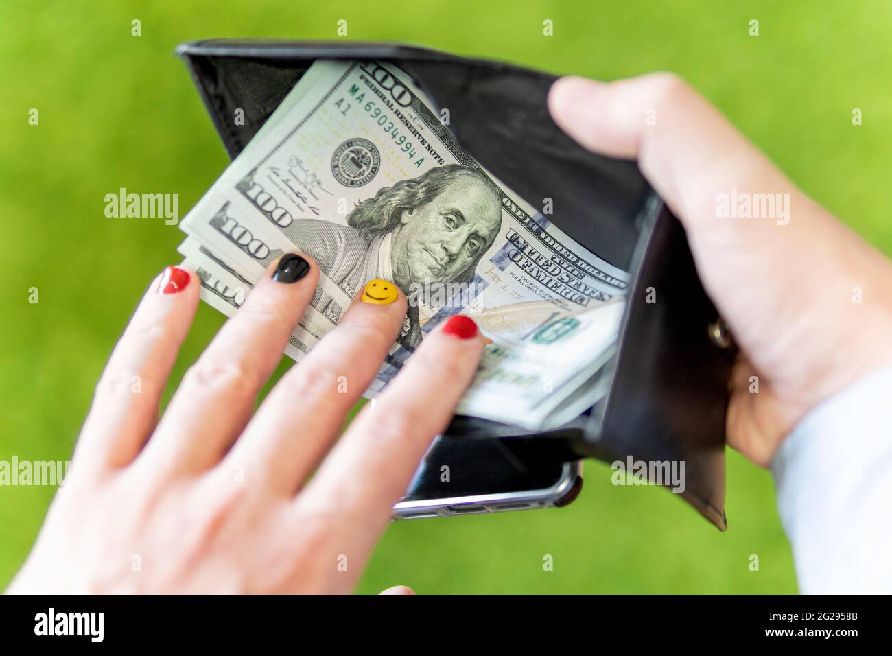 L'uomo riceve denaro dal portafoglio. Il ragazzo ricalcola lo stipendio su uno sfondo verde. Bel disegno di unghie da uomo. Foto Stock