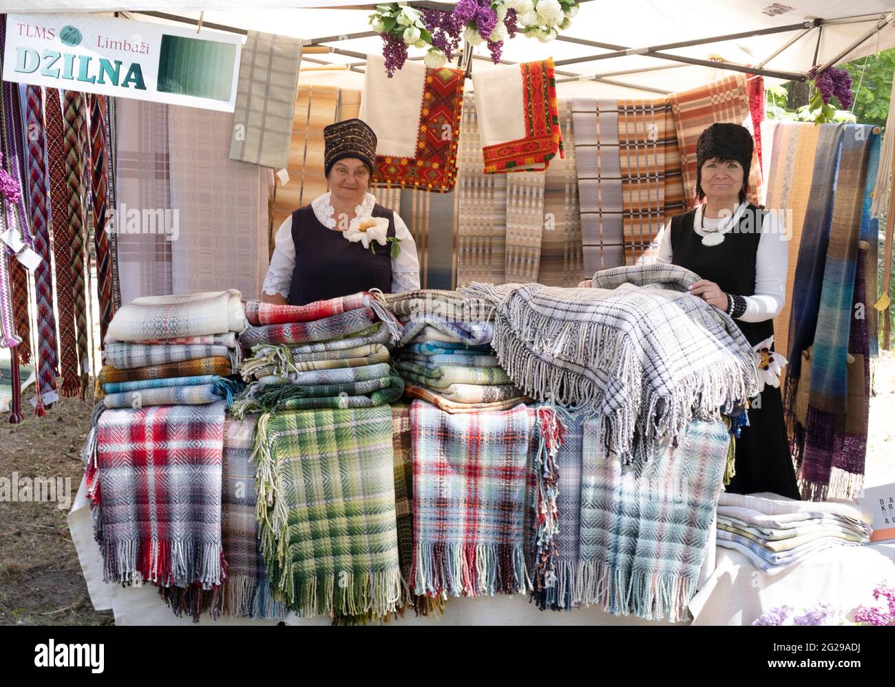 Donne artigiane allo stand vendita coperta con prodotti tradizionali e colorati di lana e cotone al Museo Etnografico all'aperto della Lettonia Foto Stock