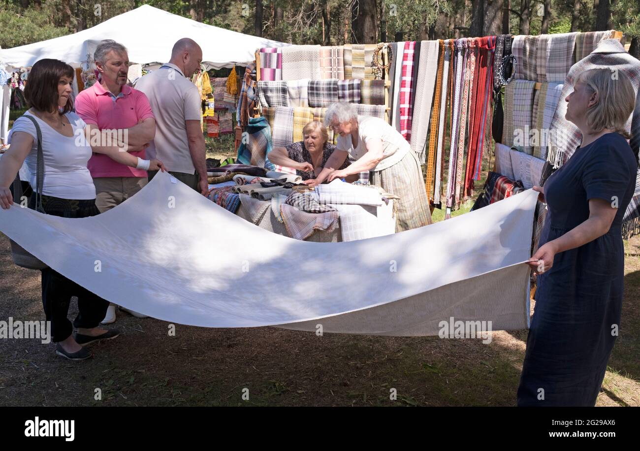 I gamberi mostrano coperta di lino e altri prodotti ad un potenziale cliente al Museo Etnografico all'aperto della Lettonia Foto Stock