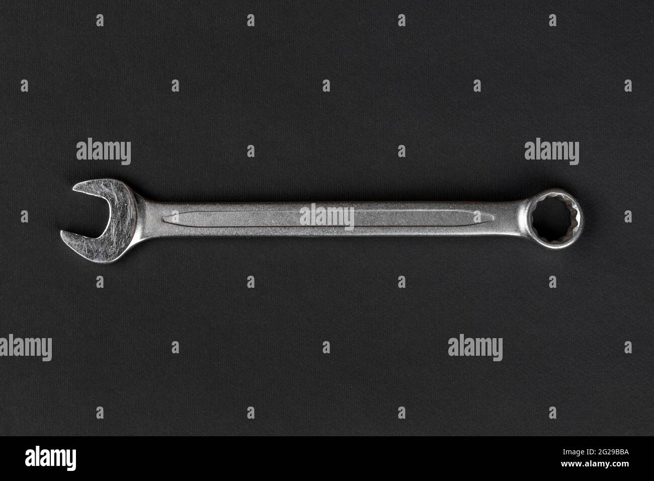 Chiave su fondo di carta nero, utensile manuale in acciaio Foto Stock