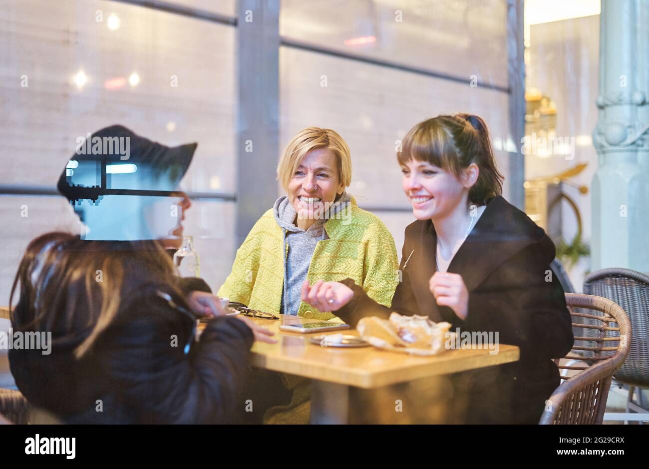 Una madre che ha un drink con le sue due figlie seduti al tavolo del bar dopo lo shopping Foto Stock