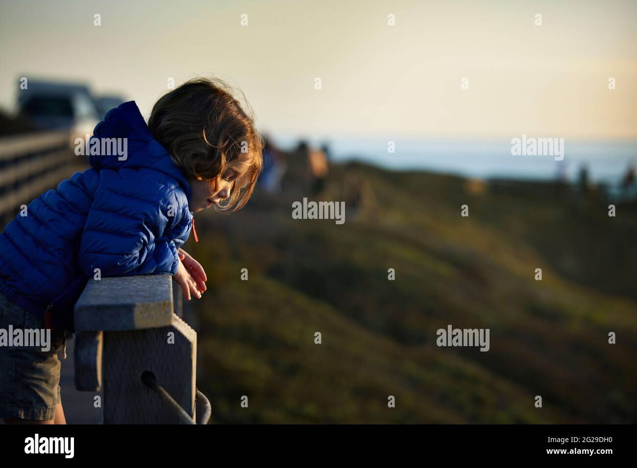Vista laterale del ragazzo che pende sulla ringhiera al punto di osservazione durante il tramonto Foto Stock