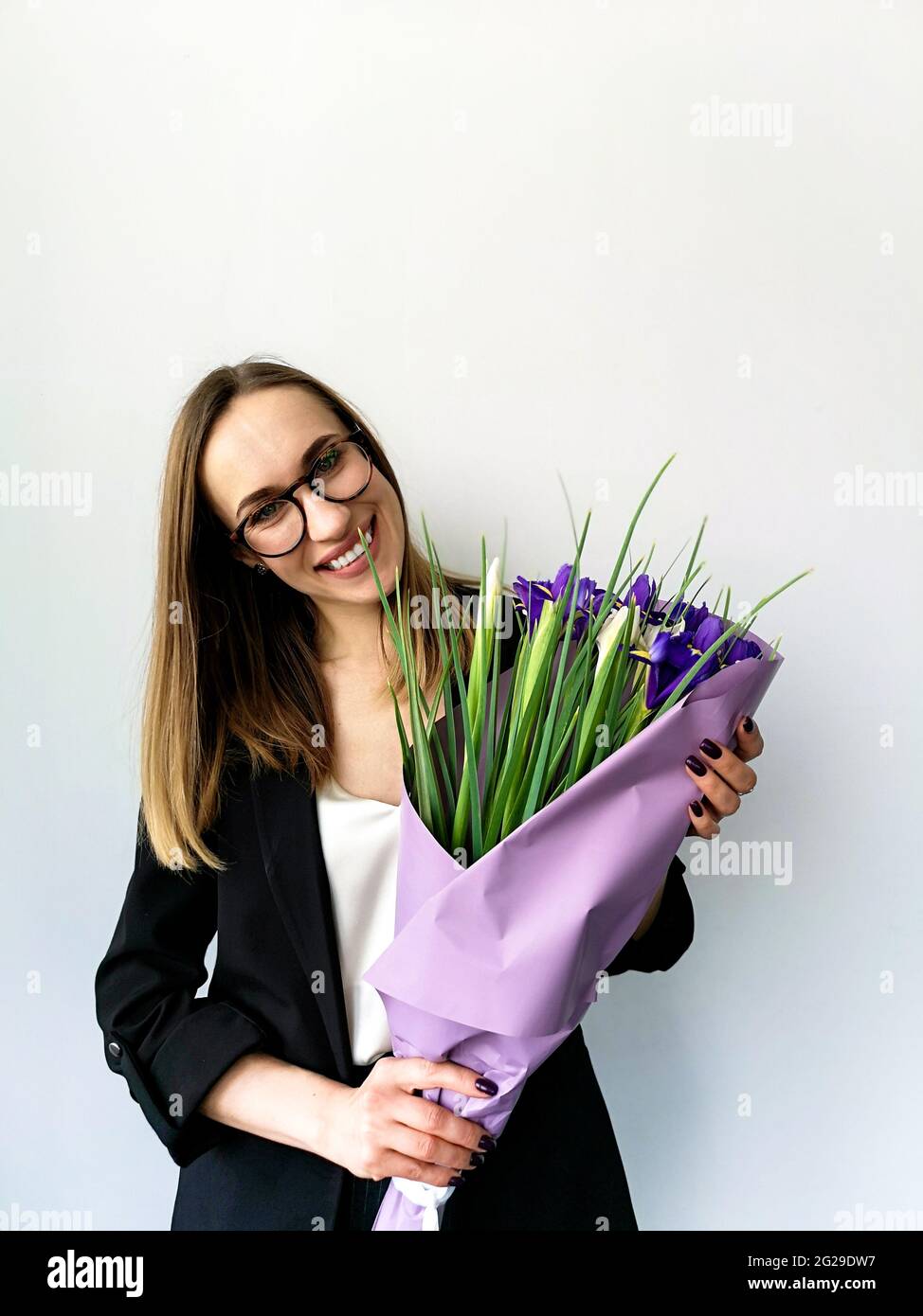 Donna d'affari che incula la testa tiene un bouquet di iris su uno sfondo bianco Foto Stock