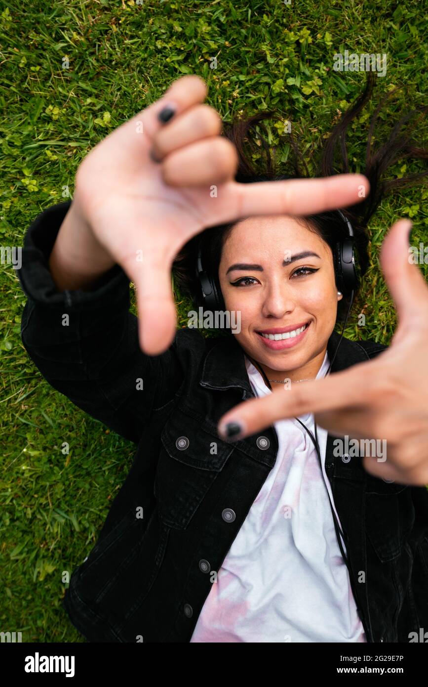Sopra il colpo di una donna allegra sdraiata sull'erba e ascoltando la musica Foto Stock