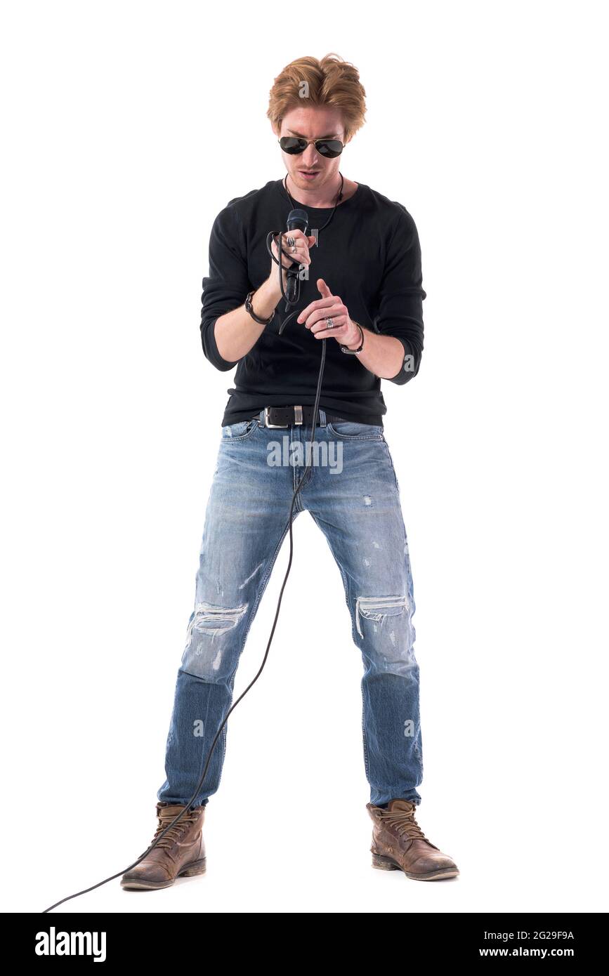 Bel giovane rocker rosso che tiene il microfono per prepararsi. Lunghezza totale del corpo isolata su sfondo bianco. Foto Stock