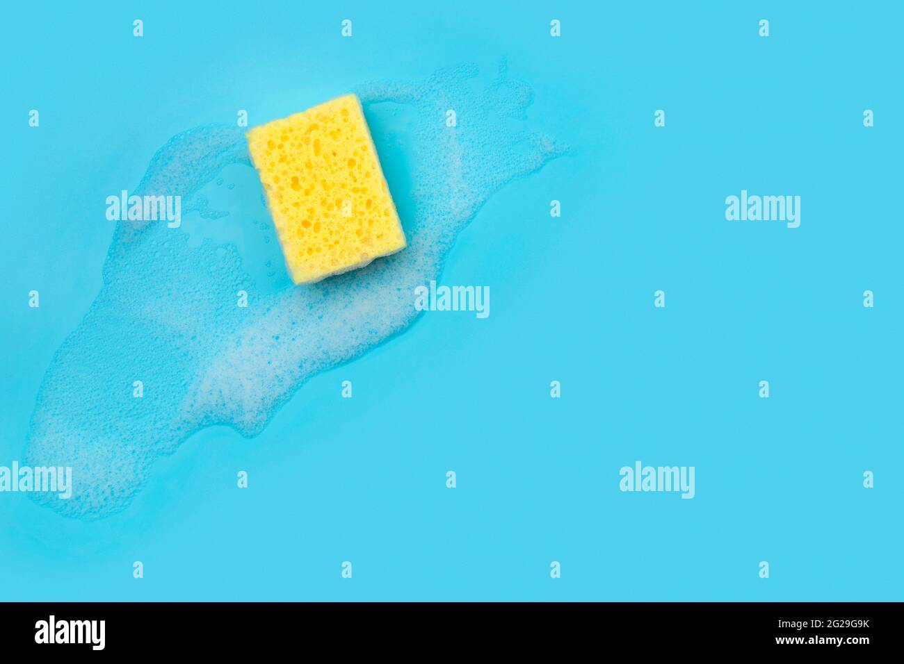 Spugna gialla con schiuma su sfondo blu Foto Stock