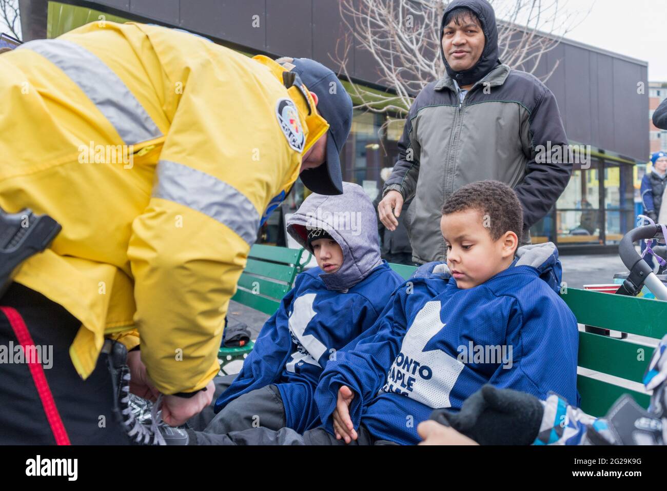 I membri della polizia di Toronto partecipano all'apertura ufficiale della pista di pattinaggio del Regent Park; hanno servito la comunità aiutando i bambini nell'apprendimento dello sci di pattinaggio Foto Stock