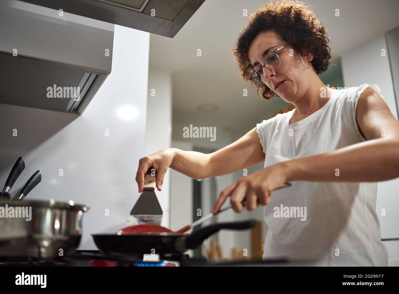 Donna che cucina con una padella sul fornello Foto Stock
