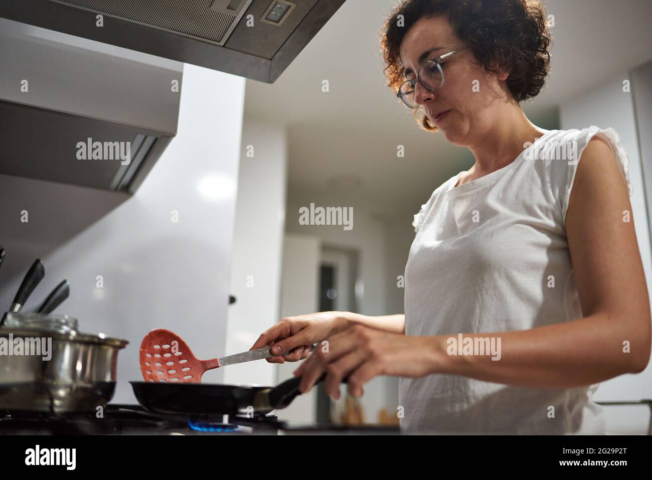 Donna che cucina con una padella sul fornello Foto Stock