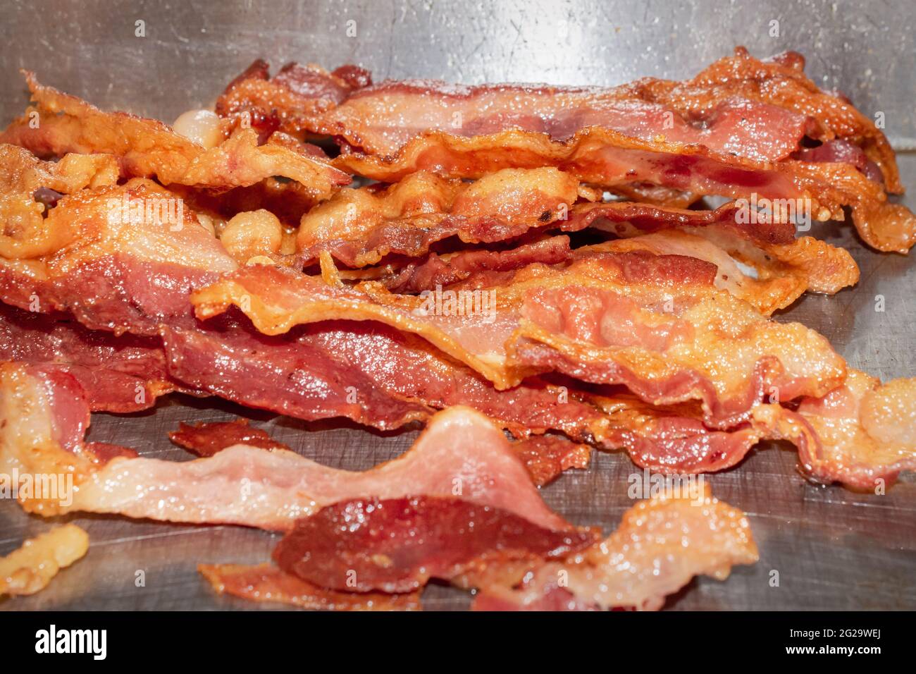 Un mucchio di pancetta cuoce su una griglia piatta in un ristorante. Foto Stock