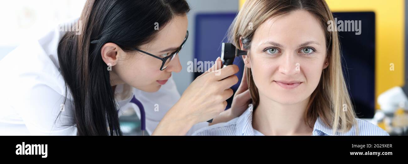Il medico esamina l'orecchio del paziente con un otoscopio Foto Stock
