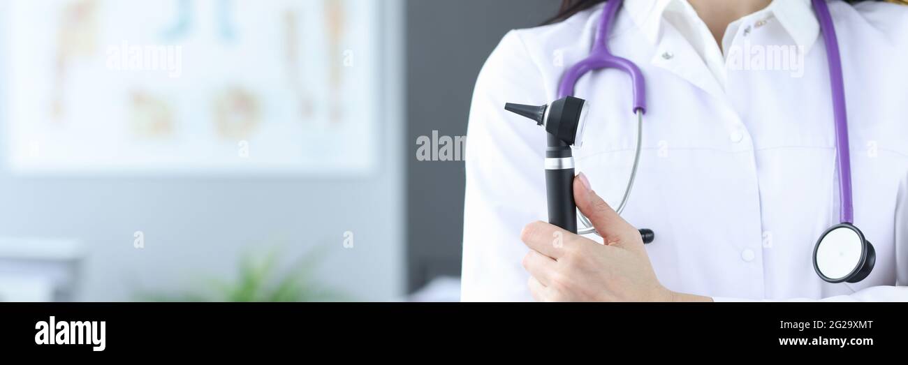 Medico in maschera protettiva tiene un otoscopio nelle mani Foto Stock