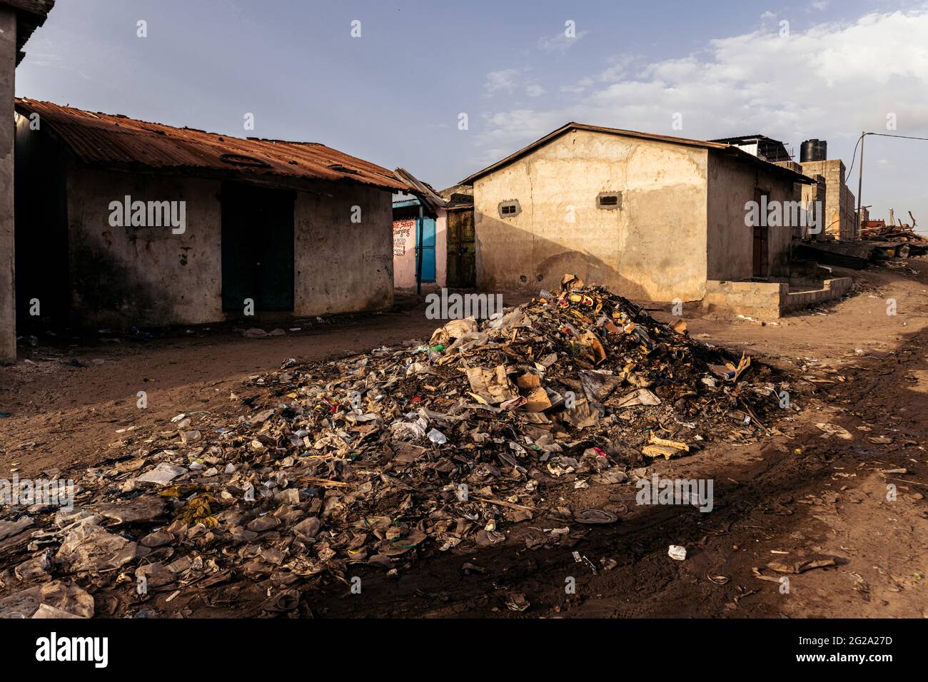 Edifici in cemento intemperie e cumulo di rifiuti su strade vuote e polverose Foto Stock