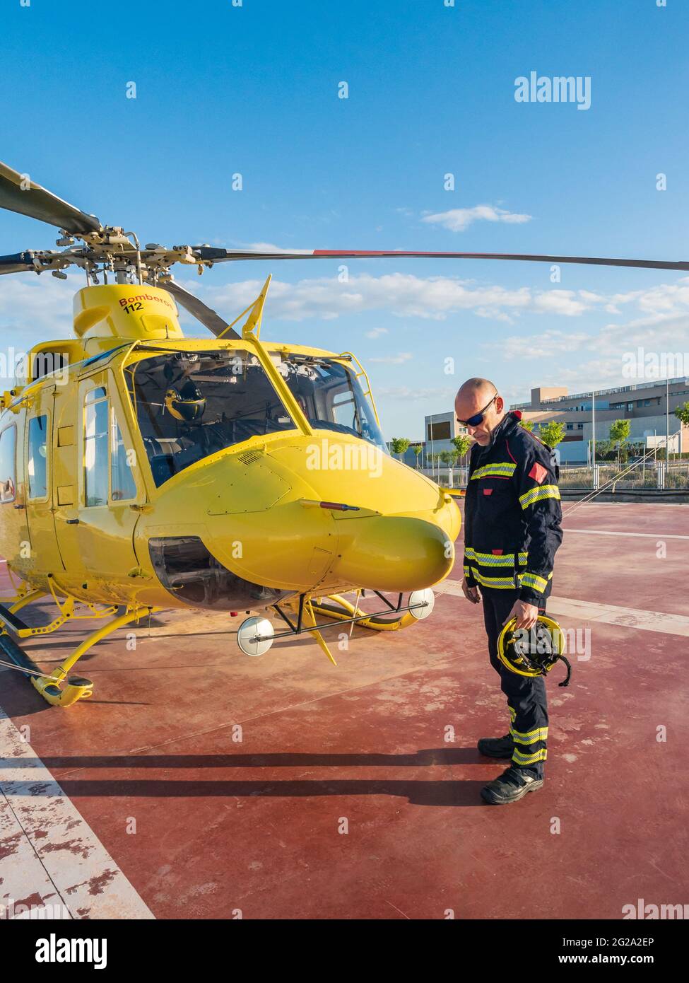 Soccorritore vigili del fuoco in piedi da elicottero giallo che tiene un  casco Foto stock - Alamy