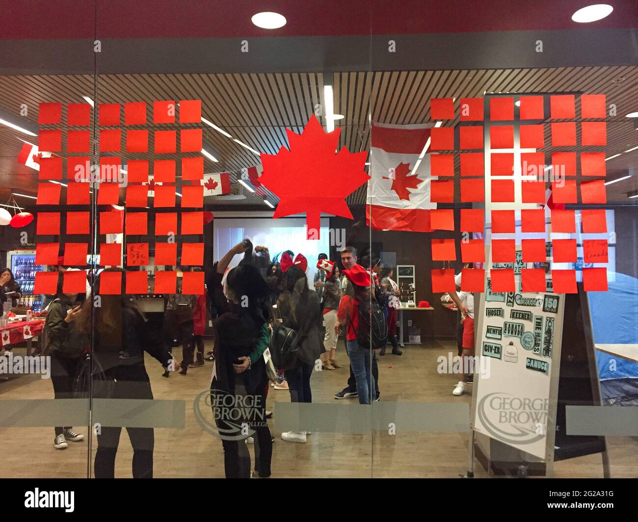 Toronto, Canada - 29 giugno 2017: Vista del campus ESL pieno di studenti che celebrano il Canada Day nel George Brown College. Bandiera DIY Canada sulla finestra. Foto Stock