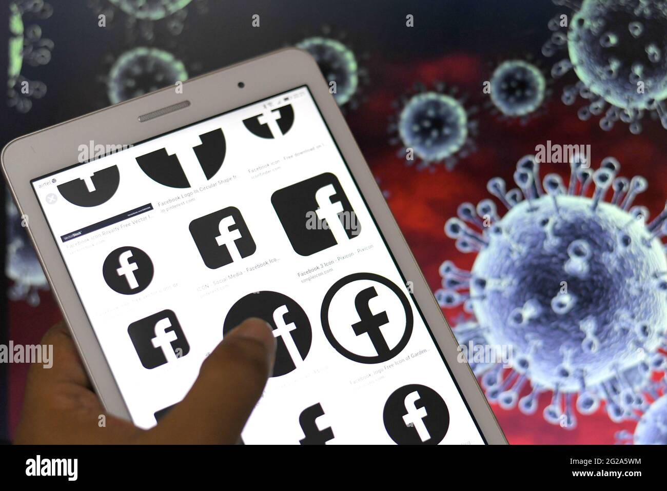 In questa illustrazione fotografica, i logo di Facebook visualizzati su un telefono Android Tablet con i simboli dei virus Corona sullo sfondo. Foto Stock