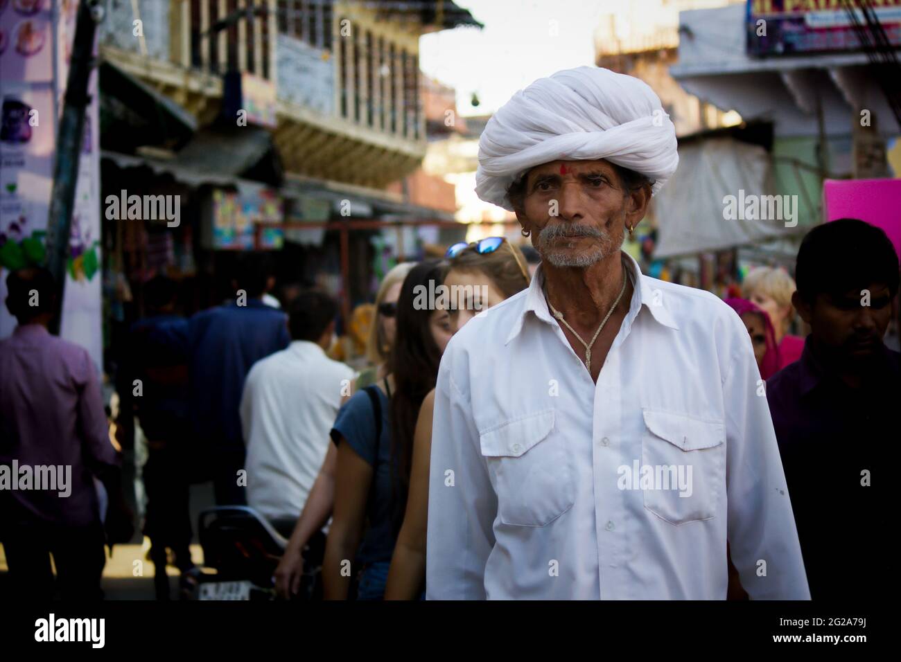 Pushkar, India - 10 novembre 2016: Un vecchio uomo Rajasthani in abbigliamento etnico tradizionale come il turbante bianco e la tipica kurta bianca che cammina in una strada Foto Stock