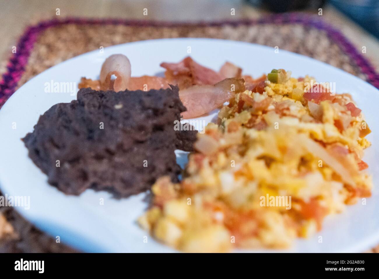 Uova in stile messicano, pancetta e fagioli fritti su un piatto bianco Foto Stock