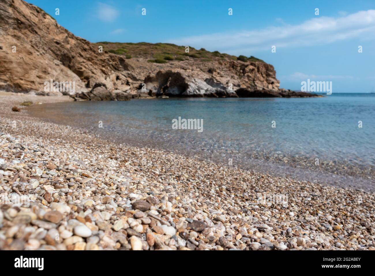 Spiaggia di ciottoli di mare selvaggio mediterraneo da vicino con scogliere rocciose e acque cristalline. Viaggia in Grecia vicino ad Atene. Estate natura laguna panoramica Foto Stock