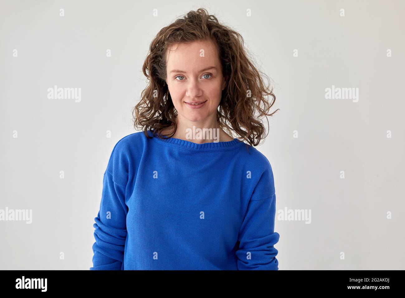 Giovane modello femminile in felpa blu oversize alla moda che guarda la fotocamera su sfondo bianco Foto Stock