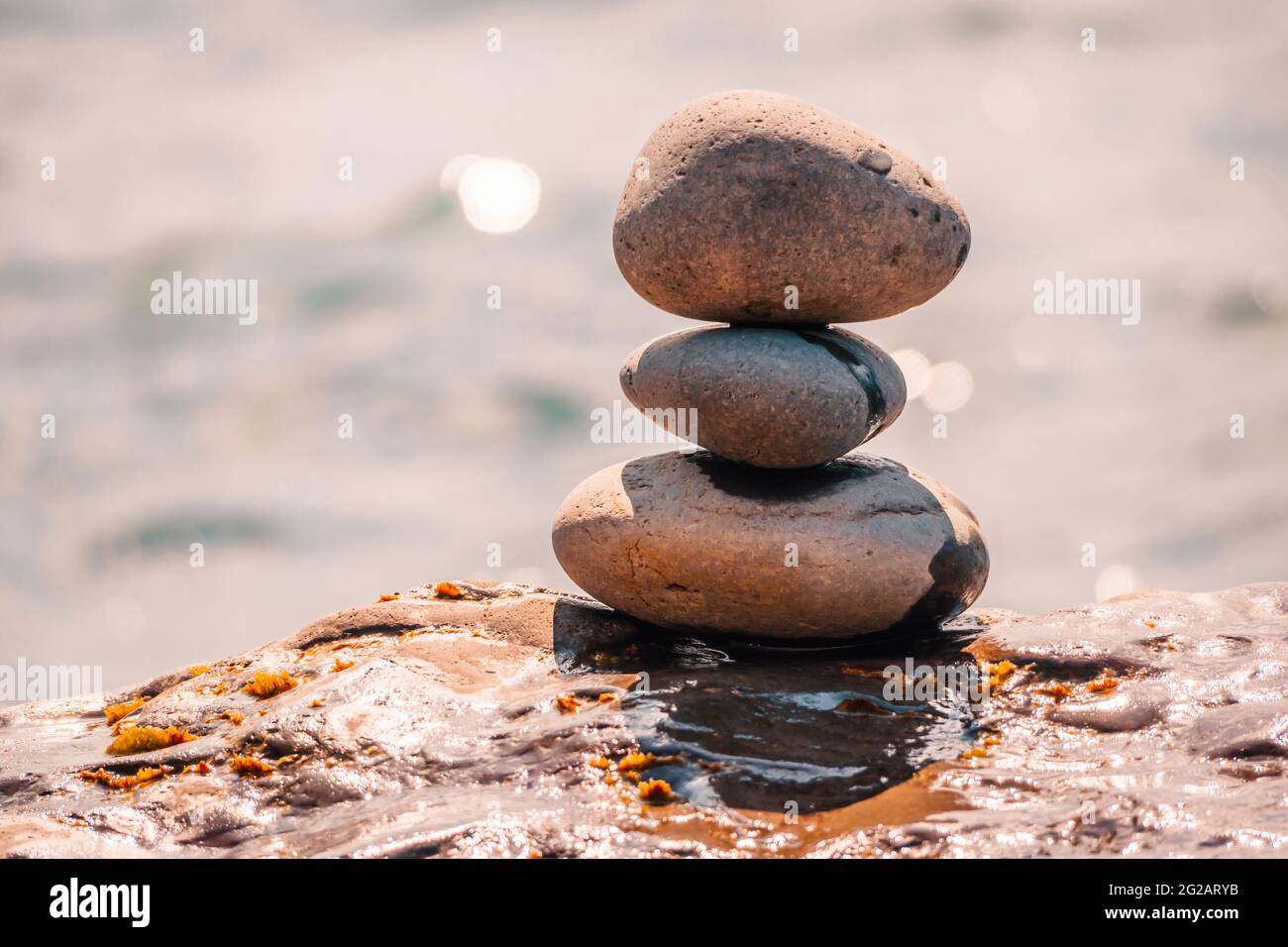 Equilibrata piramide di ciottoli sulla spiaggia in una giornata di sole. Abstract Sea bokeh sullo sfondo. Messa a fuoco selettiva. Pietre Zen sulla spiaggia di mare, meditazione Foto Stock