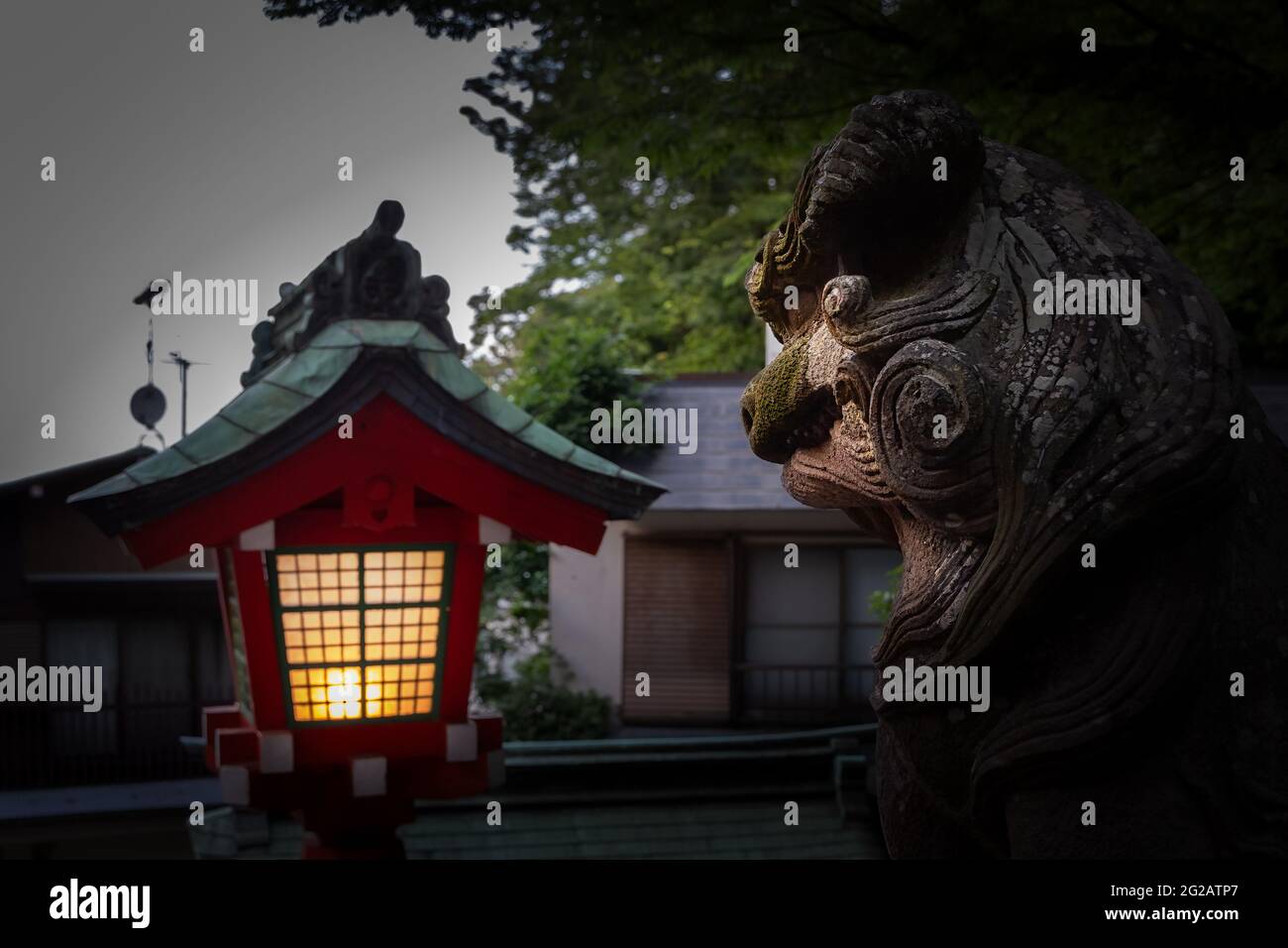 Una lanterna illumina il volto di una statua di leone su una strada di quartiere di Enoshima Island in Giappone. Foto Stock