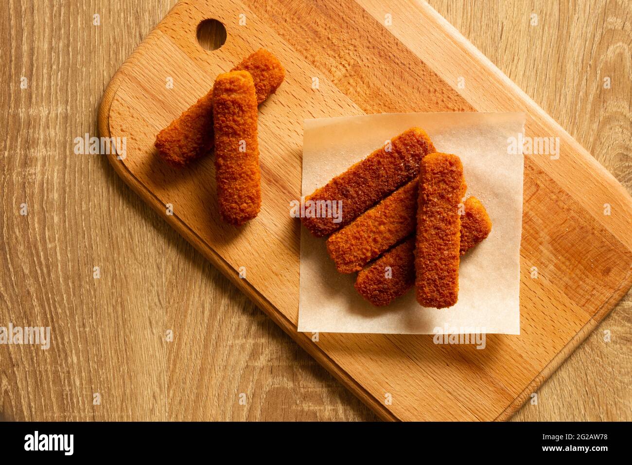 Barrette di pesce fritte su tavola di legno. Disposizione piatta Foto Stock
