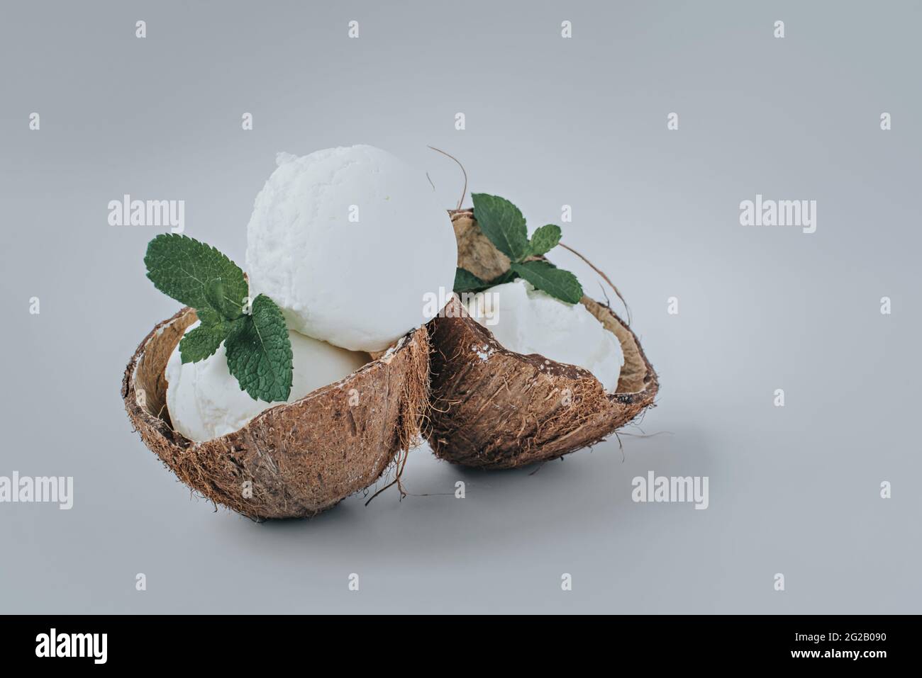 Porzione di gelato servita in noci di cocco con foglie di menta. Foto Stock