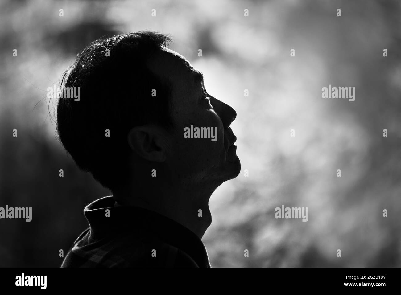 Immagine in bianco e nero di un uomo che guarda su con sfondo sfocato. Concetto di speranza. Foto Stock