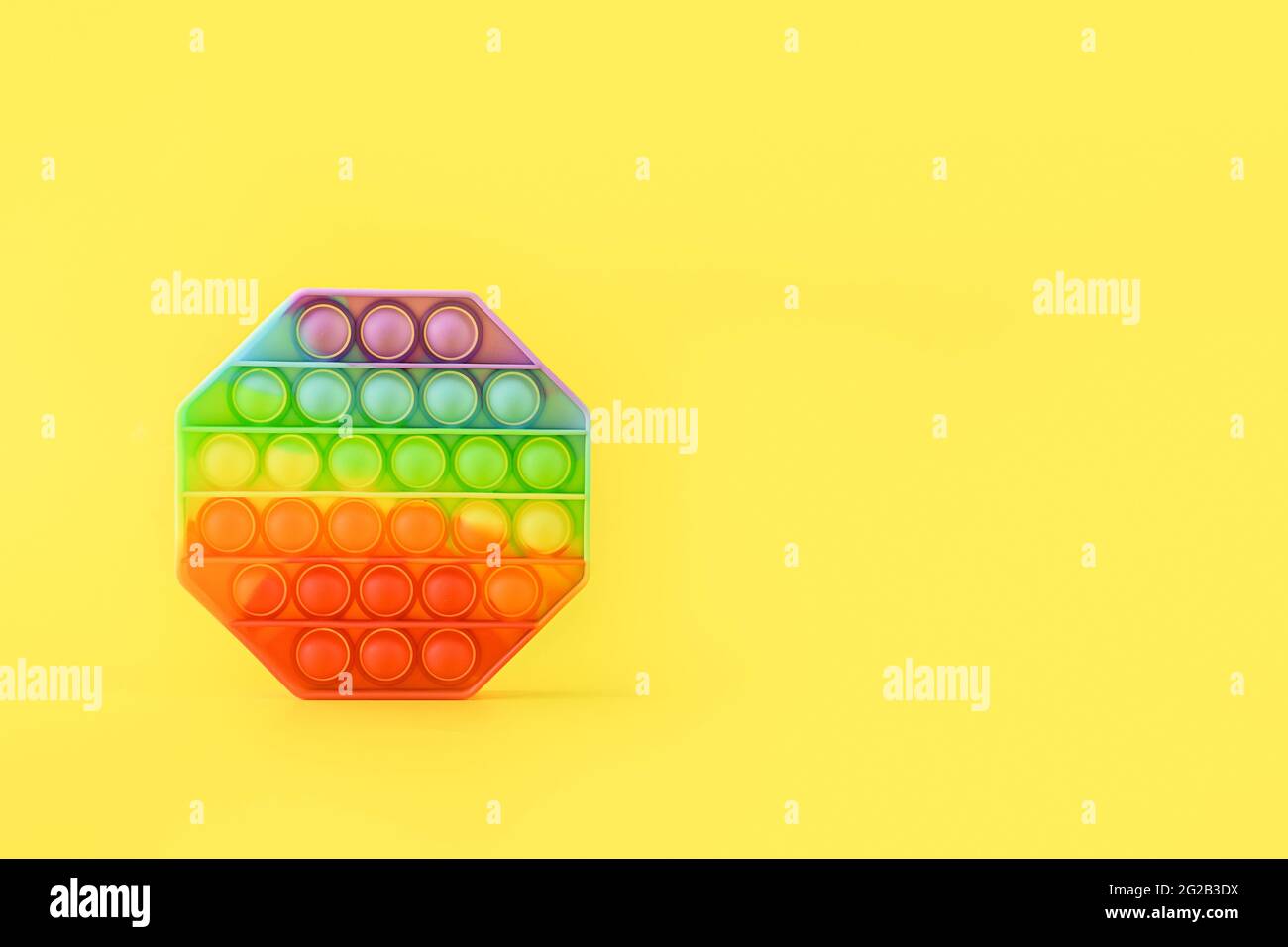 Nuovo giocattolo alla moda popolare silicone colorato anti stress Pop it per bambini su sfondo giallo. Spazio di copia. Premere Bubble pop. Foto Stock