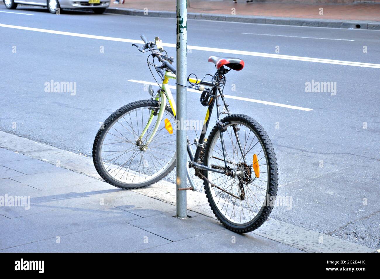 Una bicicletta che si inceppa con il palo sul marciapiede Foto Stock