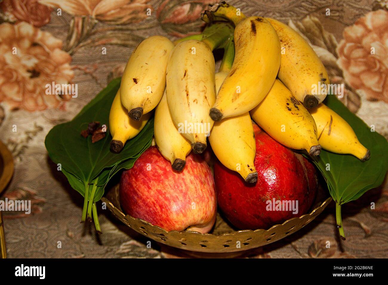 Offerta di banana, mela, melograno, foglie di betello, noce di betello messo in vaso di ottone Foto Stock