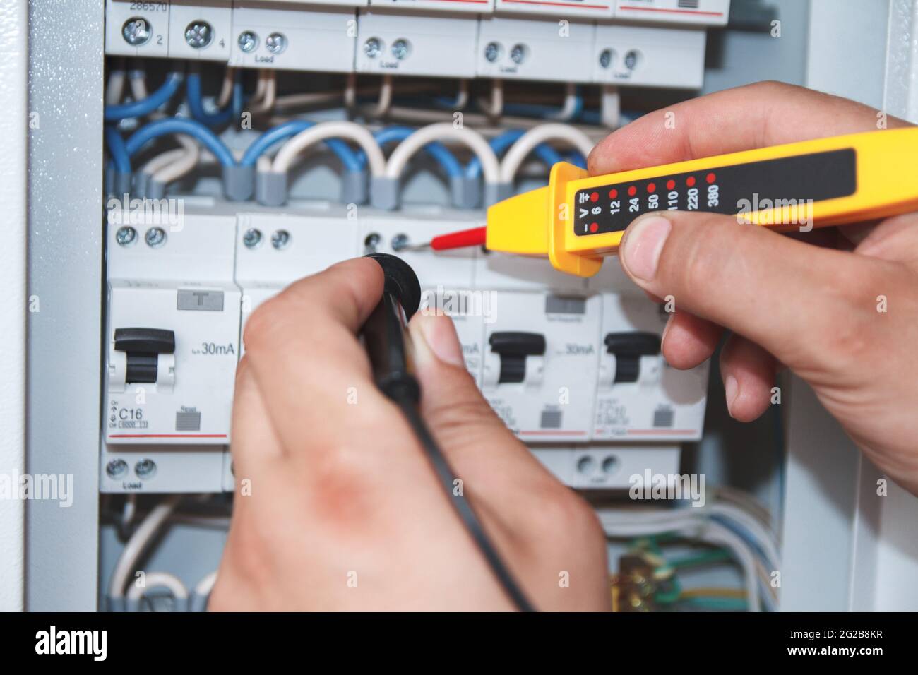 Multimetro in mano di elettricista ingegnere in armadio elettrico