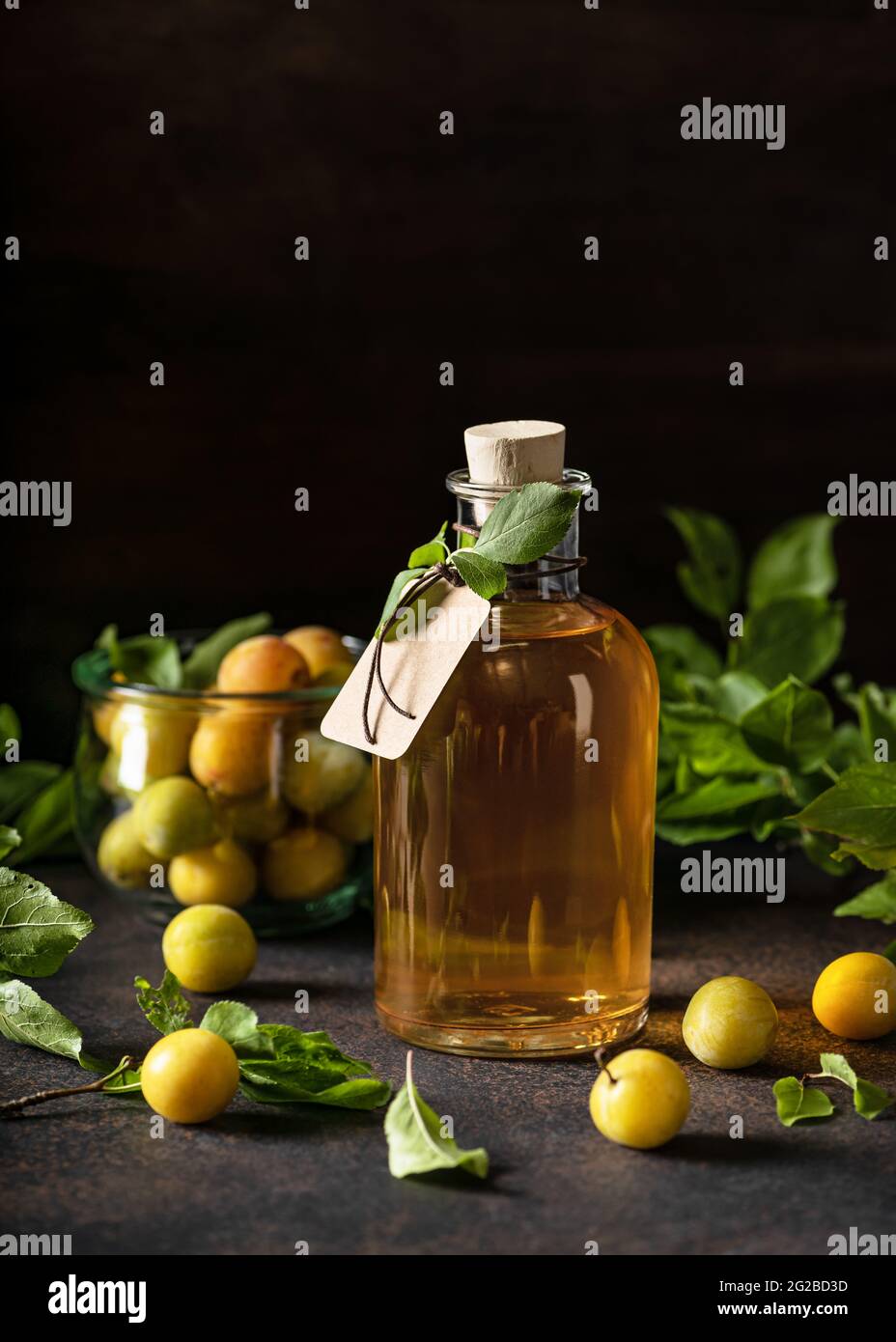 Una bottiglia di bicchiere di delizioso liquore di prugna giallo o vino su un tavolo di legno. Bevanda alcolica forte fatta in casa. Foto Stock