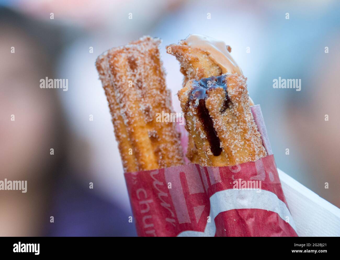 Cibo al Taste of Little Italy festival. Primo piano di churros in un involucro. Il cioccolato liquido e la panna che fuoriescono da un churro. il churro è un pa fritto-impasto Foto Stock