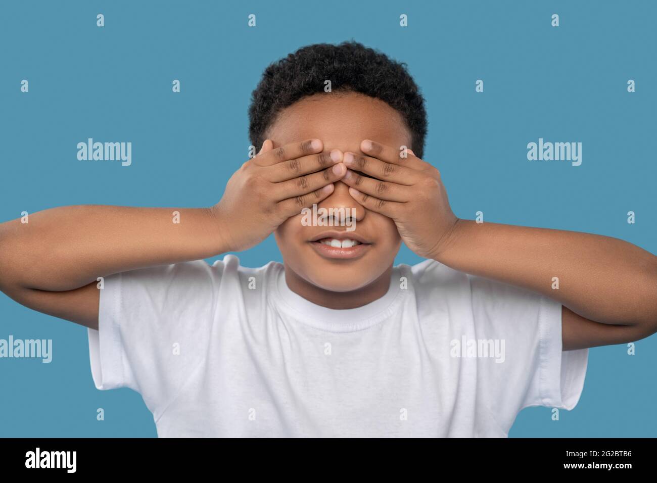 Ragazzo afroamericano che gli copre gli occhi con le mani Foto Stock