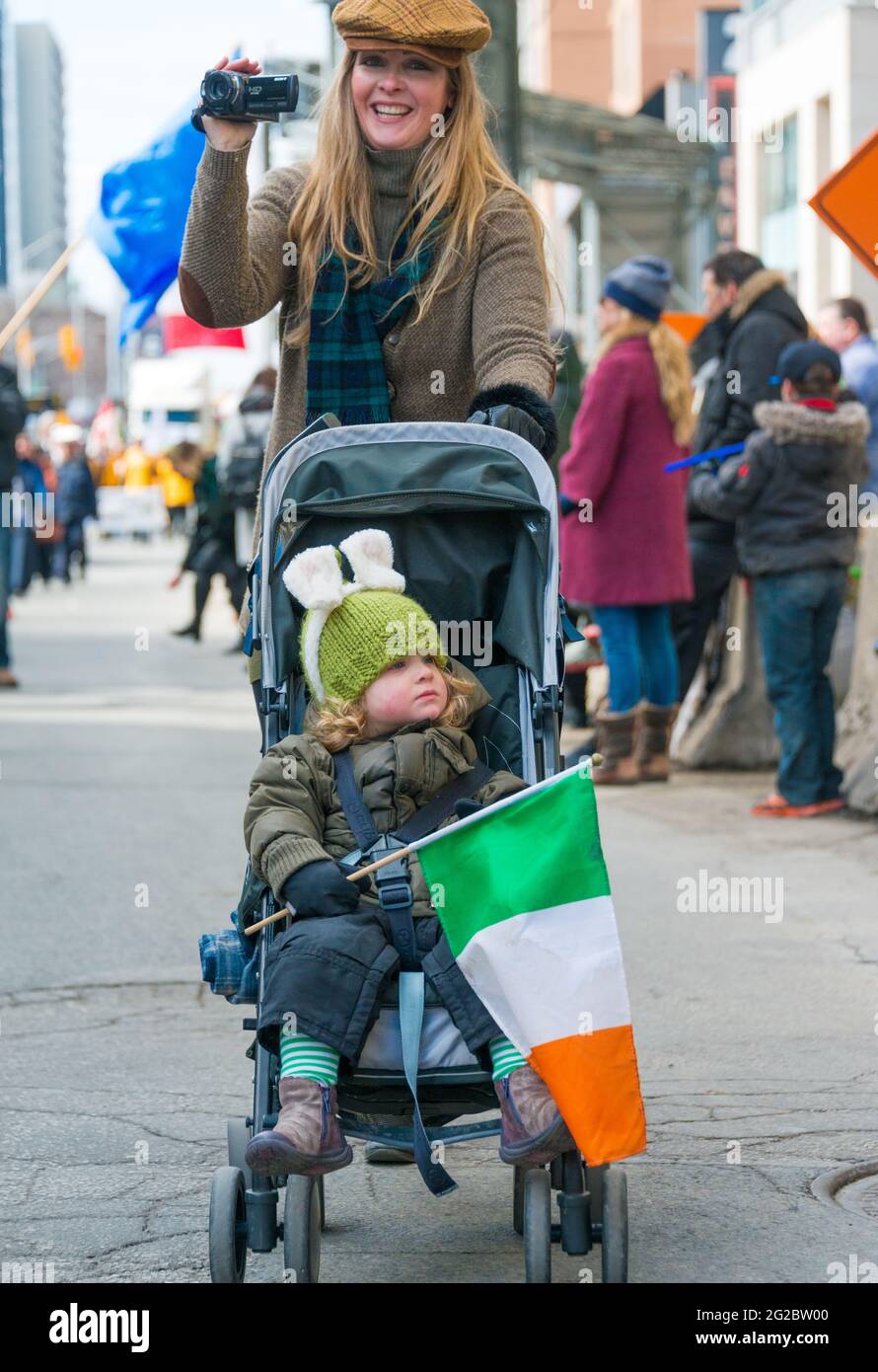 Bambino in passeggino con bandiera irlandese durante la XXVIII edizione della Parata di San Patrizio, che è la quarta più grande celebrazione del suo genere nel mondo Foto Stock