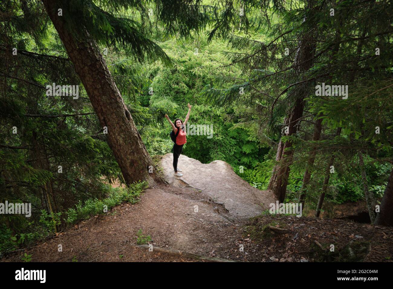 Una ragazza con uno zaino si trova sul bordo di una scogliera. Viaggia fuori città nei boschi. Campeggio. Foto Stock