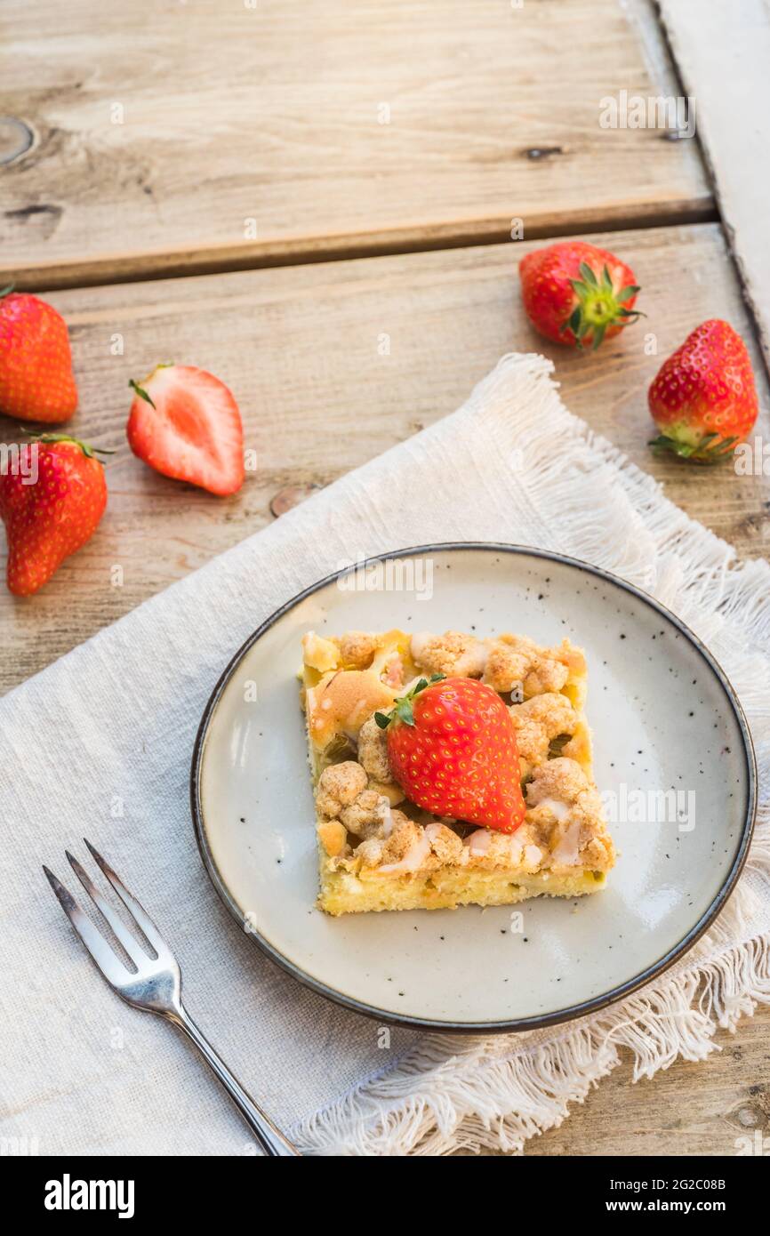 Pezzo di torta di rabarbaro e fragole su un piatto su un vecchio tavolo di legno, verticale con spazio per la copia Foto Stock