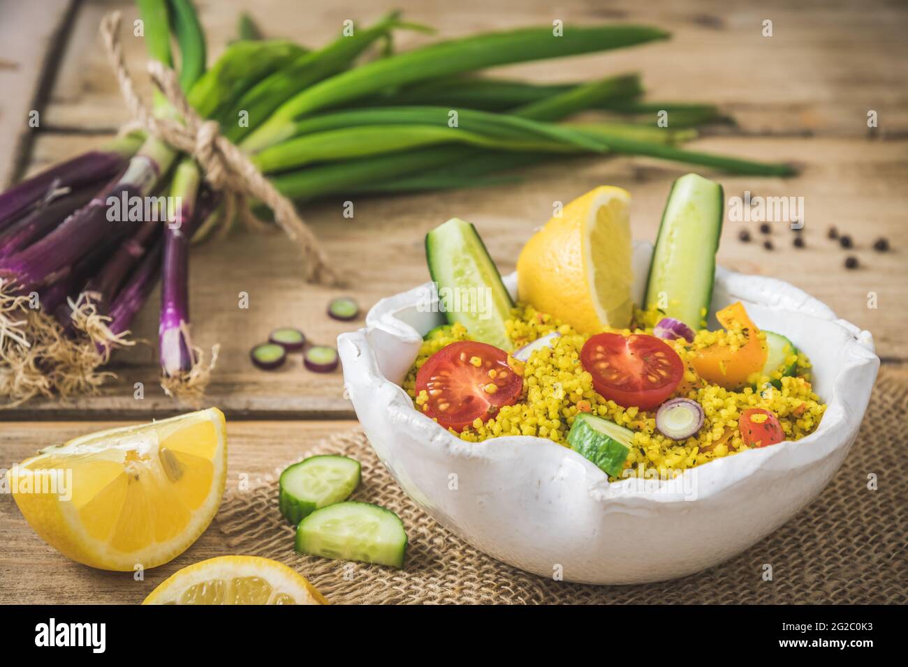 Insalata couscous con cetriolo, pomodori e cipolle in una ciotola bianca su rustico fondo di legno Foto Stock