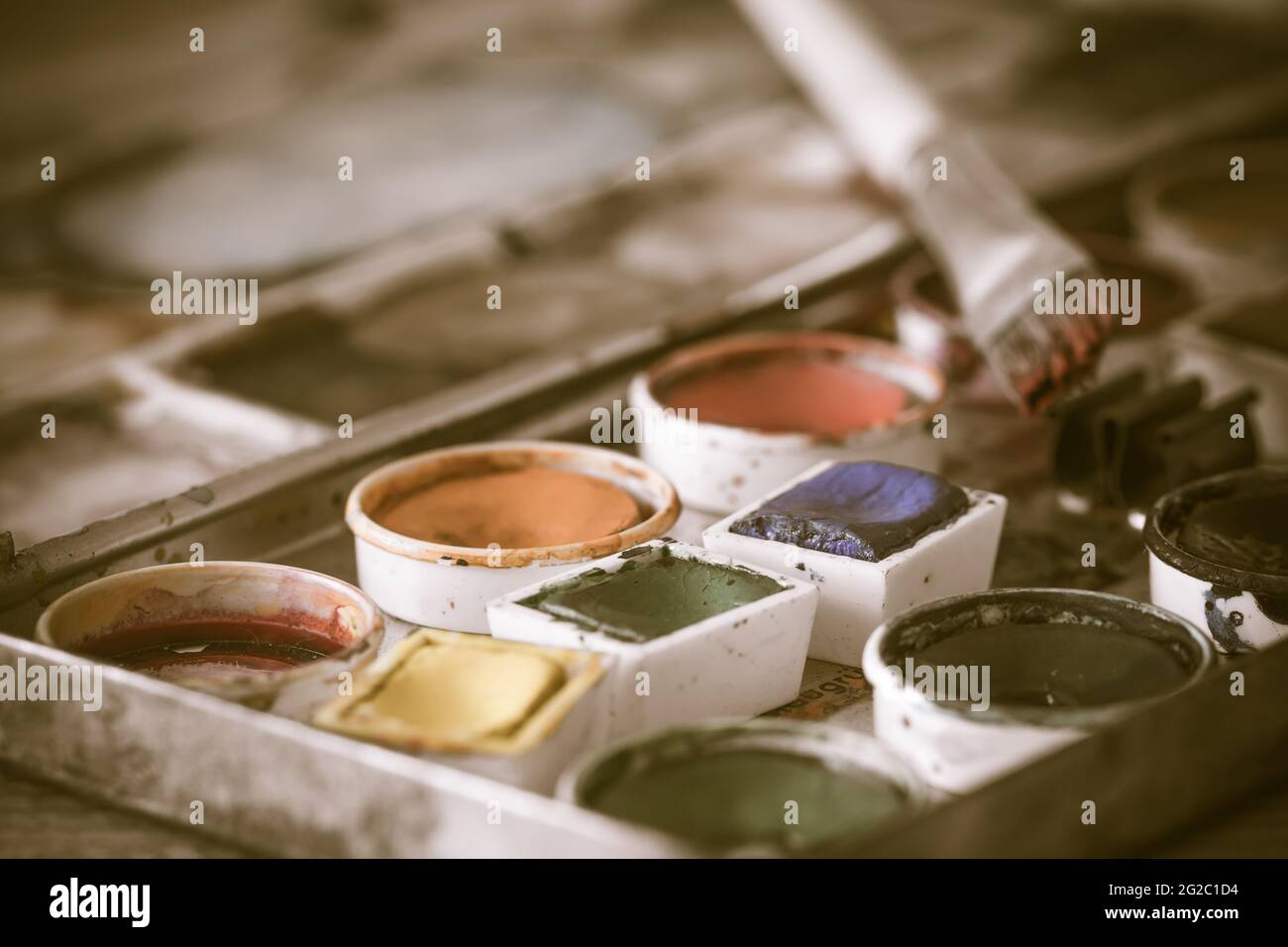 Vecchia scatola di vernice con acquerelli con pennello, antico stile vintage, colori desaturati, primo piano Foto Stock