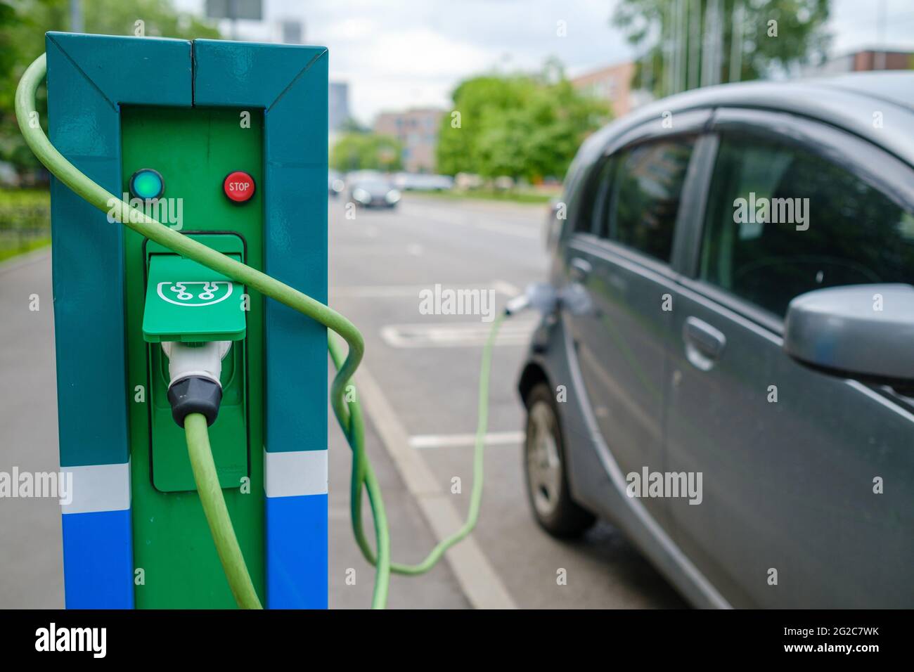 Stazione di ricarica e veicolo elettrico sul parcheggio Foto Stock
