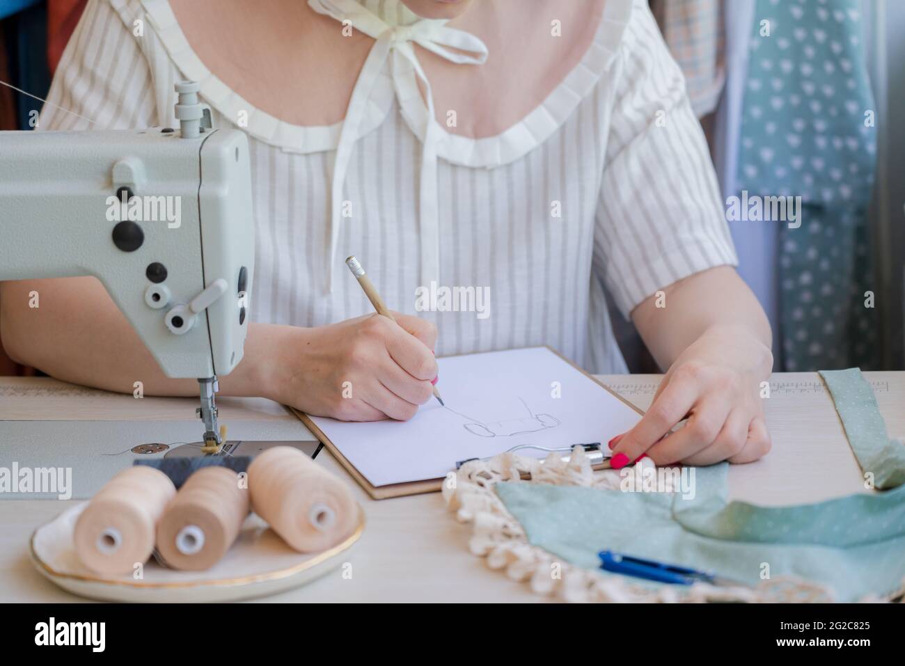 Le mani femminili del disegnatore di moda disegnano il disegno del nuovo abito alla moda Foto Stock