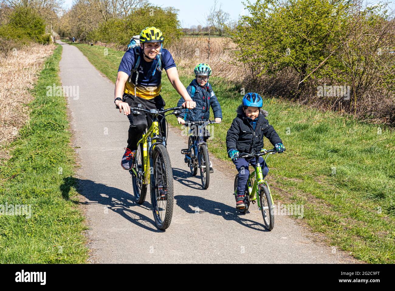 Un padre e i suoi due figli in bicicletta lungo lo York Solar System Trail vicino a Escrick, North Yorkshire, Inghilterra, Regno Unito Foto Stock