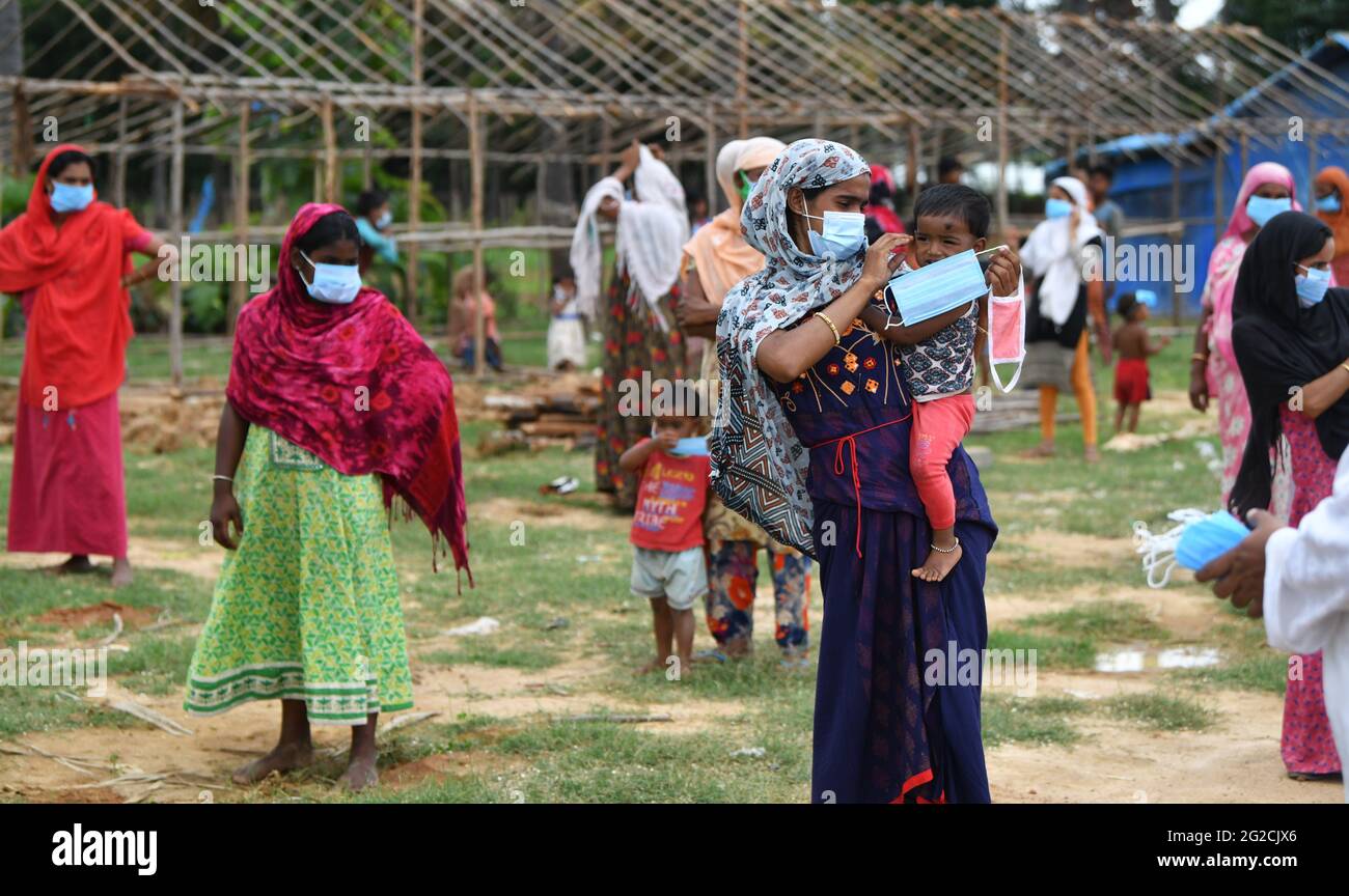 Bengaluru, India. 10 Giugno 2021. Una madre mette una maschera facciale sul suo bambino mentre attende in coda con altri rifugiati Rohingya per razioni nel loro campo di Jakkur. Anche se la gente ha intenzione di aiutare, non è possibile senza l'aiuto dei donatori dice il Dott. Shama Shareef che ha aiutato i rifugiati di Rohingya/Banjara/Bangladesh con razione di approvvigionamento su base regolare. Archana Lemanja Tomar ha colloato con GOONJ Bengaluru verso il drive di distribuzione giovedì a Bengaluru. Credit: SOPA Images Limited/Alamy Live News Foto Stock
