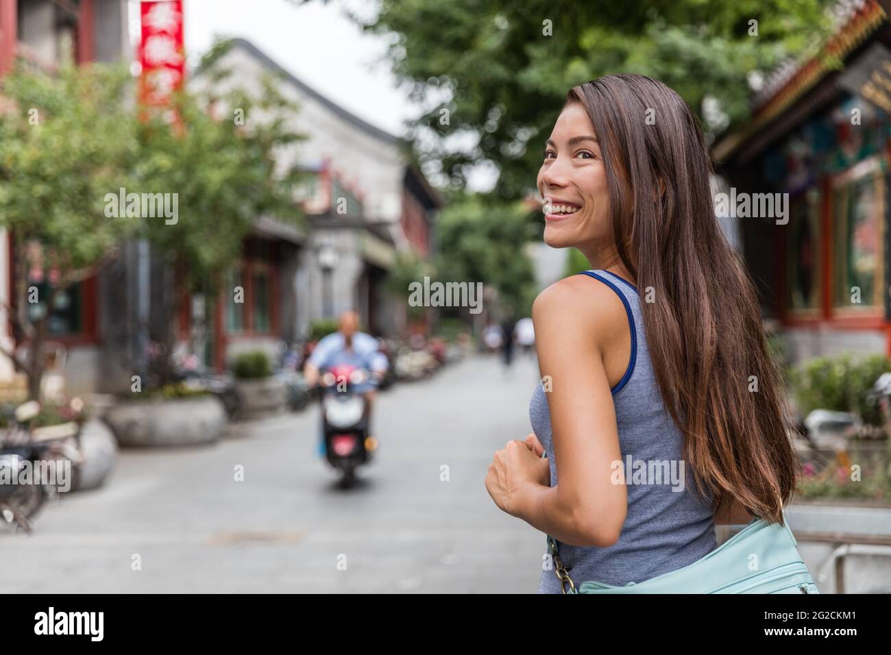 Felice ragazza turistica asiatica a piedi intorno hutong cinesi in Beijing coty, che sono un tipo di strade strette o vicoli in quartieri tipici con Foto Stock