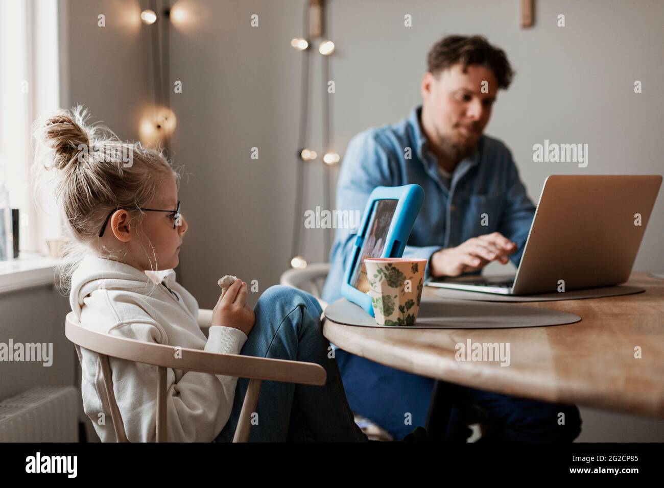 Ragazza che usa un tablet digitale, padre in background Foto Stock